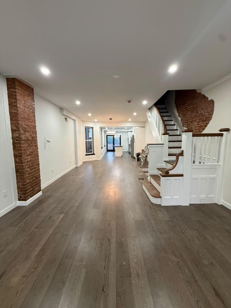 Open living room with exposed brick, wide-plank floors, and a rebuilt staircase