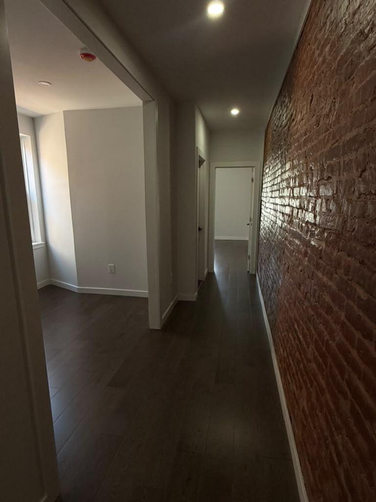 Upstairs hallway running along an exposed brick wall