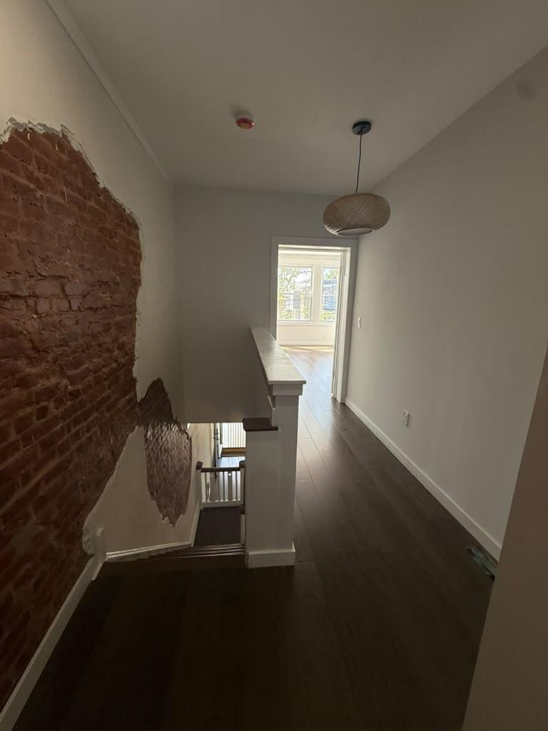 Upstairs landing with exposed brick and a woven pendant light